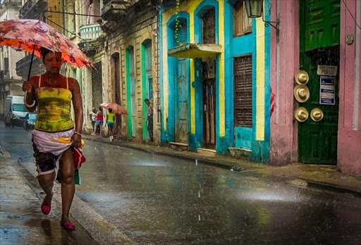 A woman walks past the colourful, cracking facades of a rain-soaked street in Havana, Cuba. Overall winner: 2014 Sunday Times Travel Photographer of the Year.