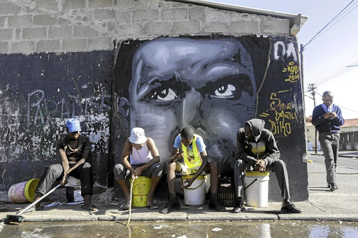 A group of youngsters in Langa, Cape Town, relax against a wall bearing a painting of Steve Biko. Picture: DAILY DISPATCH