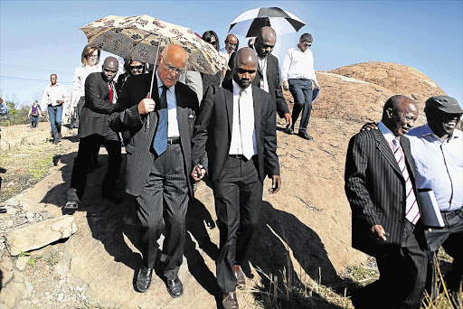 Retired judge Ian Farlam (with umbrella) visits the site of the Marikana massacre. He heads the commission of inquiry into the August 16 2012 tragedy.