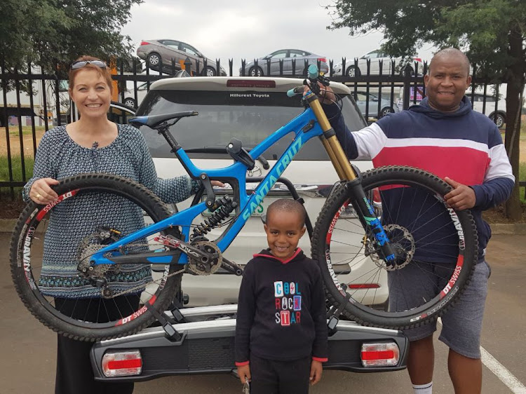 Lynne Jackson is reunited with her son's R170,000 bicycle, which was found by Gauteng policeman Willy Skobane and his son, Bongani.