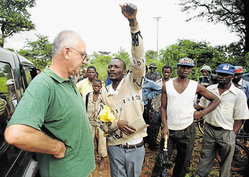 LAND GRAB: The leader of a group of peasants indicates where his followers will settle on Rockwell Farm, owned by farmer Andreo Malus, left, in Concession, 50km north of Harare, in 2000.