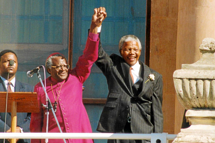 The late Anglican archbishop Desmond Tutu and Nelson Mandela salute the crowd from the balcony of the Cape Town City Hall.