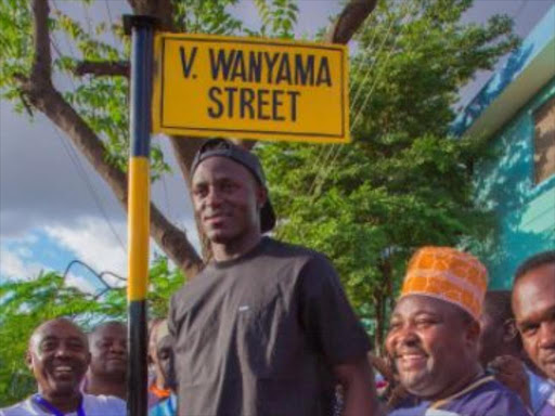 Harambee Stars captain Victor Wanyama stands next to a post of the eponymous street in Dar es Salaam, June 24, 2017. /COURTESY