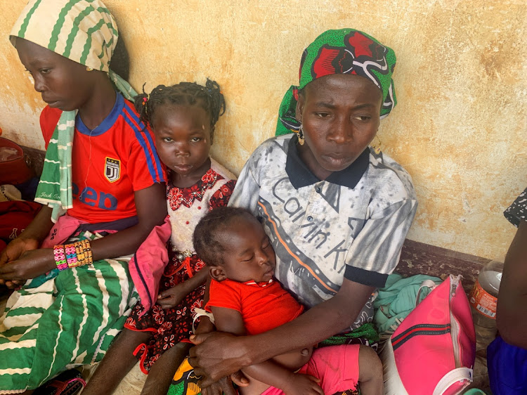 A woman who fled the violent rebellion in Central African Republic (CAR) sits with her family as they wait for their identification process in the border town of Garoua Boulai, Cameroon on January 7, 2021.