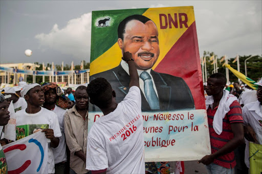 A man gives last touches to a painting of incumbent Congolese President Denis Sassou Nguesso at the closing rally of his electoral campaign in Brazzaville on March 18, 2016. Congo holds presidential elections on March 20, with incumbent Denis Sassou Nguesso seeking a third term after a controversial change to the constitution that allows him to extend his 32-year grip on power. / AFP PHOTO / MARCO LONGARI
