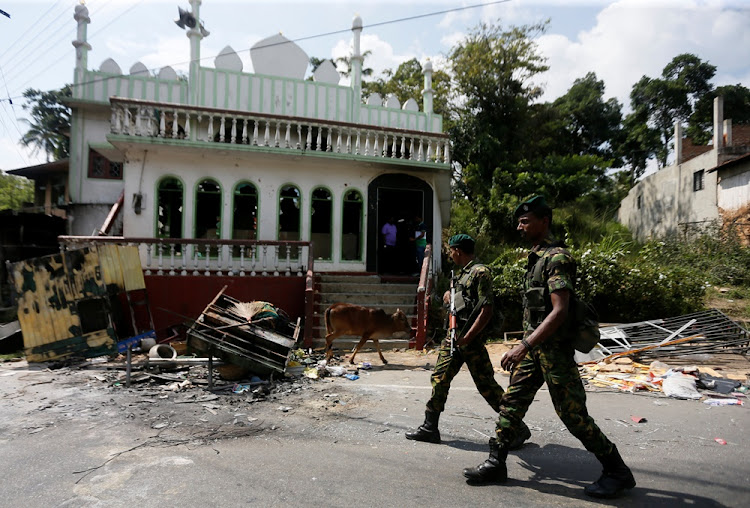 Sri Lanka's Special Task Force soldiers walk past a damaged mosque after a clash between two communities in Digana, central district of Kandy, Sri Lanka March 8, 2018.