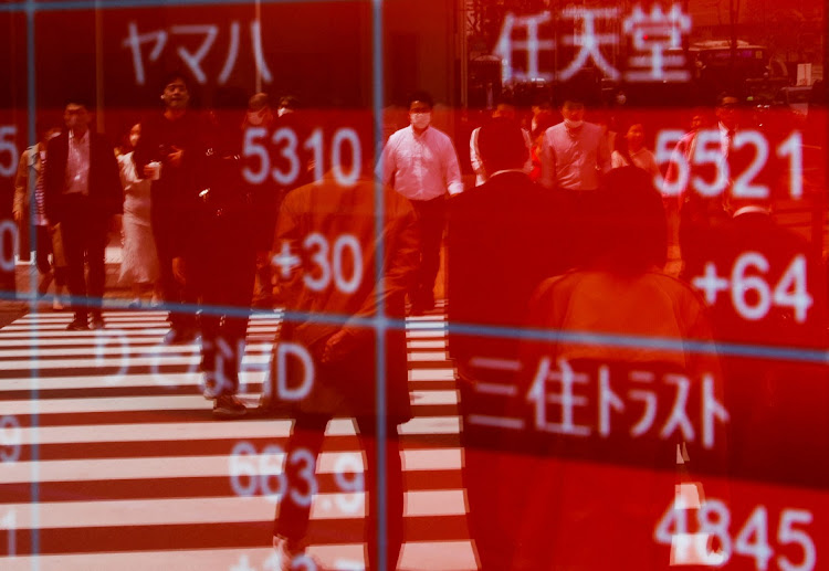 Passersby are reflected on an electric stock quotation board outside a brokerage in Tokyo, Japan. Picture: REUTERS/ISSEI KATO
