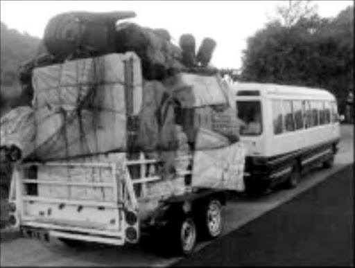 SKY HIGH: An overloaded trailer, hitched to a bus, travels on the N4 highway towards Mozambique. Pic. Riot Hlatshwayo. 06/07/08. © Sowetan.