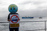 A member of Extinction Rebellion holds up a placard as the Akademik Alexander Karpinsky, a Russian polar explorer ship, arrives in Cape Town harbour on January 28 2023.