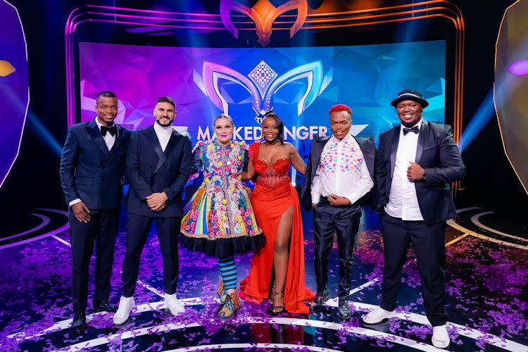 Award-winning singer-songwriter Holly Rey (centre) wins The Masked Singer SA. She stands alongside detectives Sithelo Shozi and Skhumba on her left and J'Something as well as host of the show Mpho Popps on her right.