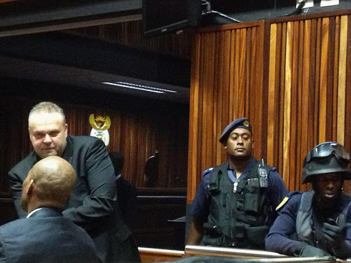 Czech fugitive Radovan Krejcir lounges in palm ridge magistrates court talking to his co-accused Desai Lupondo as police tactical response team members stand guard ahead of their bail application.