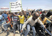 WANTING MORE: Striking platinum miners march near the Anglo-American Platinum mine near Rustenburg, North West Province, on Friday. Amplats fired 12000 workers on the same day, and said 5000 were not likely to be rehired