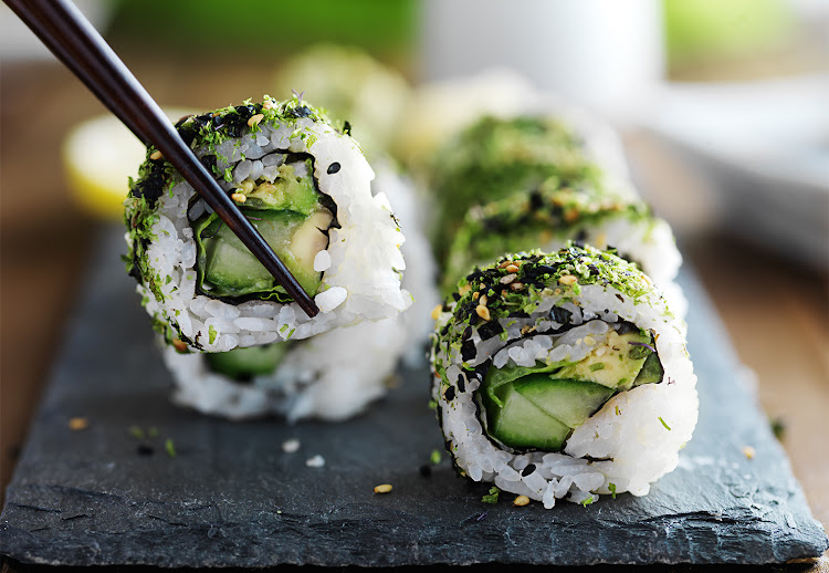 Green eating: kale and avocado sushi roll with chopsticks