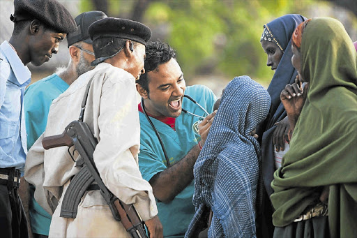 Paediatrician Amith Ramcharan examines a child outside a hospital in Mogadishu, Somalia. Countless lives have been saved by a team of doctors from South Africa Picture: SIMPHIWE NKWALI