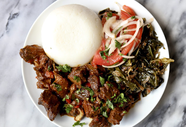 Ugali and wet fry beef accompanied with kachumbari and sukuma wiki