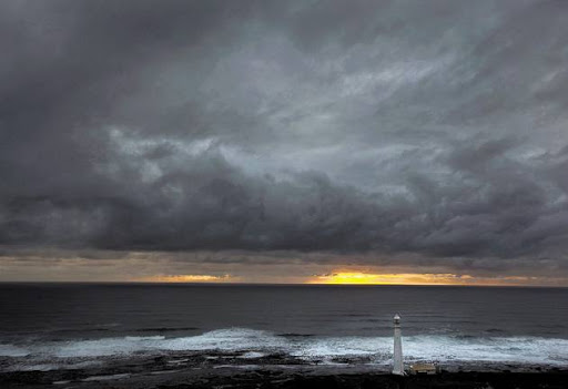 Heavy storm clouds hang threateningly over the Slangkop Lighthouse, at Kommetjie, near Cape Town. File photo.