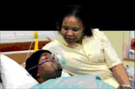 CARING WIFE: Tebogo at her husband's bedside in hospital. Vuyo Mokoena was diagnosed with a brain tumour last Thursday. His family has asked South Africans to pray for him. Pic. Antonio Muchave. 14/05/08. © Sowetan.