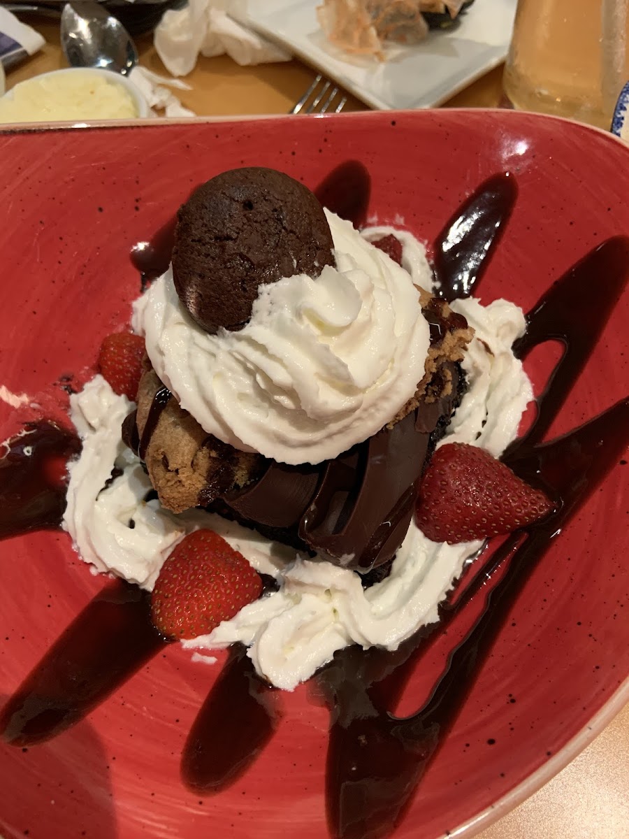 Gluten free brownie topped eith chocolate mousse, a huge GF chocolate chip cookie, whipped cream, a smaller GF chocolate cookie, chocolate sauce, and fresh strawberries.