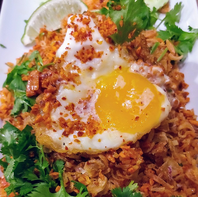 Spicy | tangy | savory | slightly sweet tomato base sauce tossed with broccoli | tomatoes | white onions | topped with fried shallots | fried egg | cucumber slices | lime wedge | togarashi seasoning.