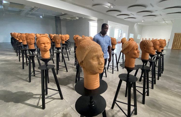 A man walks across a set up of terra cotta heads, a French woman collection representing the remaining Chibok school girls in captivity in Lagos, Nigeria, on November 29, 2022.