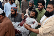 Men move an injured man after a suicide attack during an election campaign meeting, outside a hospital in Quetta, Pakistan July 13, 2018. 
