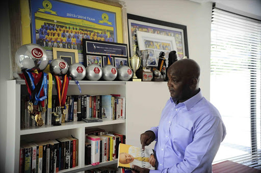 Pitso Mosimane shows off one of his books in his Houghton, Johannesburg home. The Sundowns coach is an avid reader, although his study is also filled up with his many accolades he's won over the years, including a record five successive coach of the month awards last season. PhotoS: Thulani Mbele