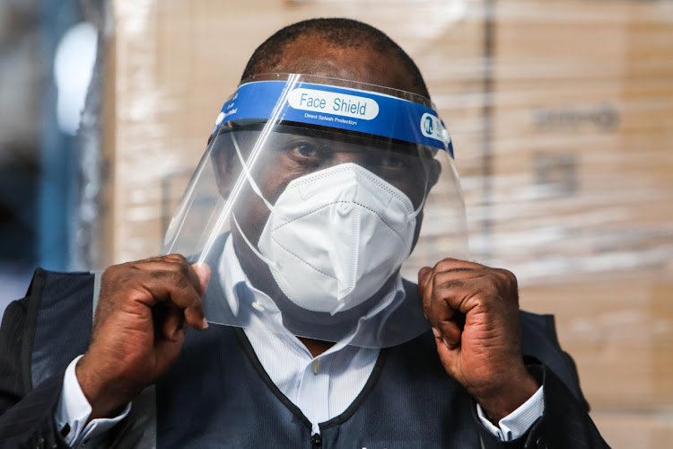 President Cyril Ramaphosa tries on personal protective equipment donated to health-care workers. Allegations about corruption in the procurement of goods to combat Covid-19 are surfacing. File photo.