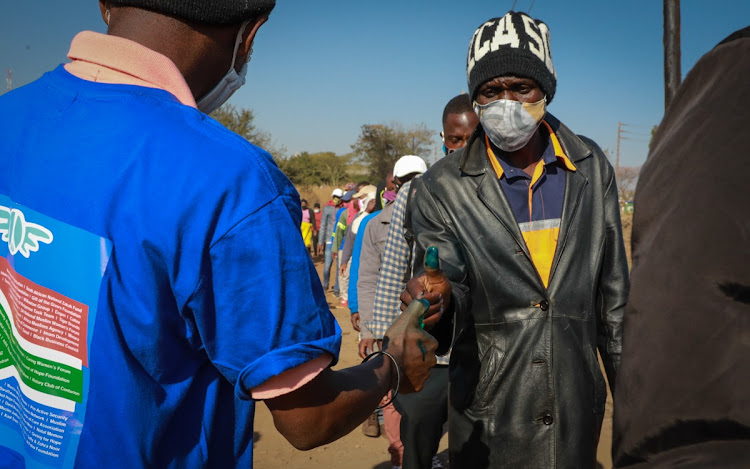 Hundreds of people stand in line to collect food parcels at Iterileng informal settlement.