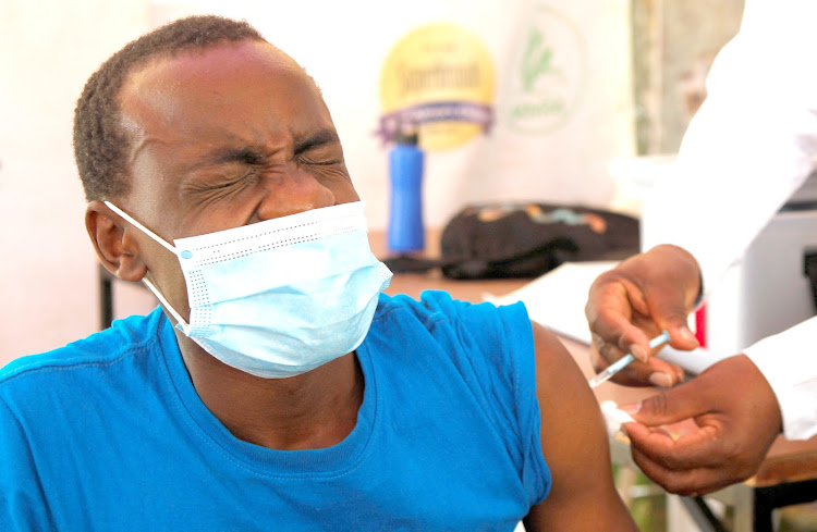 A man reacts as he receives a booster shot vaccine against Covid-19 at a medical clinic makeshift tent to enhance the booster programme in Nairobi on January 19, 2022.