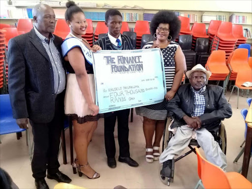 Picture: SUPPLIED FINANCIAL LIFT: Pupil Khuselo Nkunkuma, centre, receives R4 000 from Zokhanye Funani, second from the left, and Zothando Funani, second from the right. Left is the principal of Thomas Ntaba secondary school, Themba Funani, and right is Lucas Boy Ngcwangu Picture: SUPPLIED