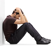 Depressed man sitting on the floor with his head down.