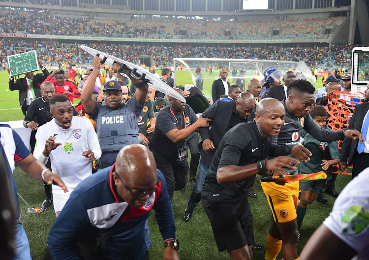 Kaizer Chiefs head coach Steve Komphela runs for cover along with Free State Stars' players and match officials after a Nedbank Cup semifinal, which Stars won 2-0, turned violent as Chiefs fans invaded the pitch baying for Komphela's blood shortly after the final whistle at Moses Mabhida Stadium in Durban.