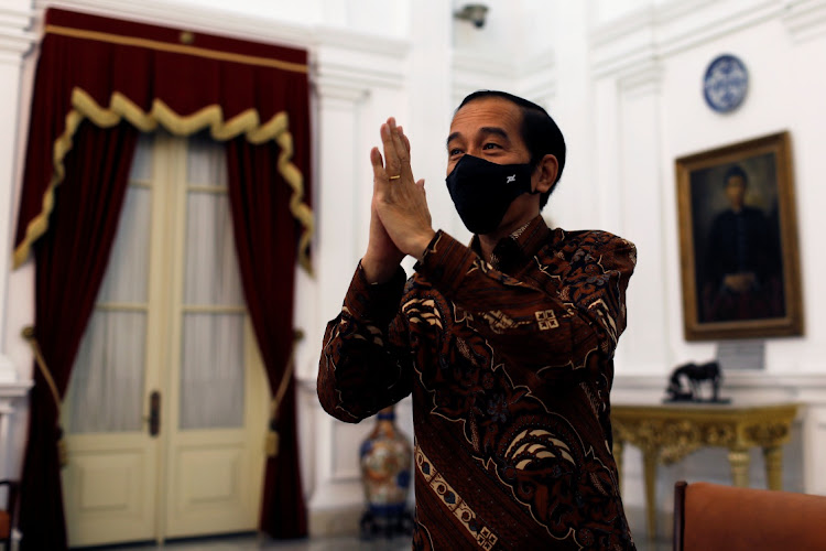 Indonesian President Joko Widodo wearing a protective mask greets Reuters' reporters after an interview at the Presidential Palace in Jakarta, Indonesia, November 13, 2020.