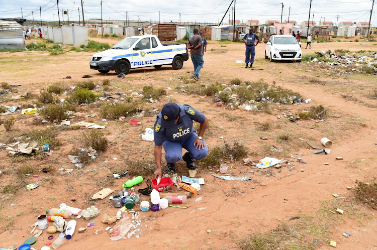 SEEKING CLUES: Police comb the large field in Motherwell, strewn with litter and rotting food, in which four children were playing hours before they died on Sunday.