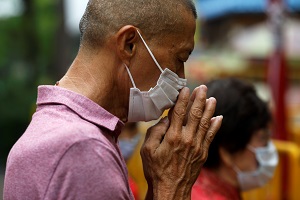A man wearing a protective face mask prays outside a temple, amid the coronavirus disease (Covid-19) outbreak, in Singapore.