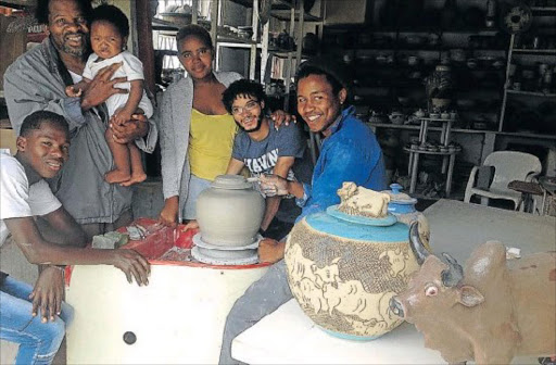 POTTERS’ PRIDE: Swazi-born master ceramicist Meshack Masuku holds his nine-month old son as his workshop apprentices, from left, Asiphe Gaxela, 20, Buseka Gaxela, 17, Freddie Luffun, 21, and Sityhilelo Ngozi, 25, look on Picture: DAVID MACGREGOR