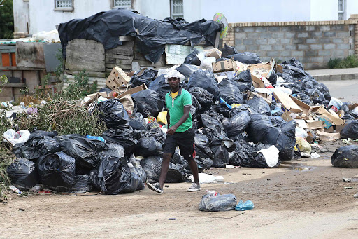 HEALTH HAZARD: A resident of Nompumelelo township in Beacon Bay walks past a pile of trash yesterday Picture: MARK ANDREWS