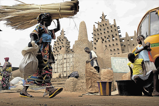 A woman walks past the Grand Mosque of Djenne on market day. Nearly 10000 annual tourists visited Djenne, a Unesco World Heritage-listed town, in previous years. Since Mali's coup d'etat in late March, after which Islamist rebels took control of the country's northern two-thirds, less than 20 tourists have visited Djenne, according to the local tourism board
