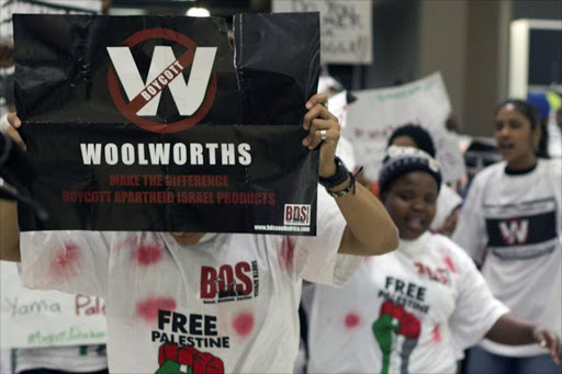 A demonstrator shows a placard inside Woolworths at Killarney mall in Johannesburg on October 25, 2014. A BDS (Boycott, Disinvest and Sanction) action targeted again the high end South African retailer Woolworths accused by the demonstrators of using products coming from the Occupied Palestinian Territories. The police arrested several dozen demonstrators.