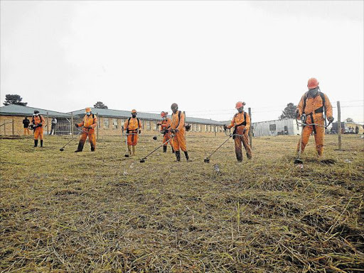 WORKING FOR GOOD: Inmates from the Mthatha Correctional Centre cut grass at Zimele Senior Secondary School in Ikhwezi township in July last year as part of the 67 Minutes for Madiba campaign. They also fixed broken doors and windows at the school, painted walls and roofs, and delivered about 90 school desks they helped to repair Picture: SIKHO NTSHOBANE