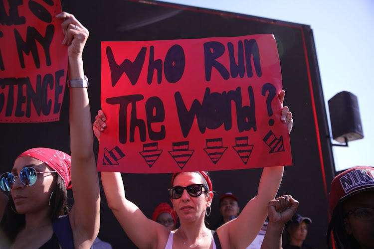 Women hold placards as they take part in the #TotalShutdown march in Pretoria on August 1, 2018.