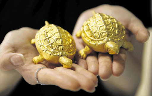 An employee holds replicas of turtles made of gold at a jewellery shop in Seoul this week. Gold has been on the up with no signs of an imminent retreat