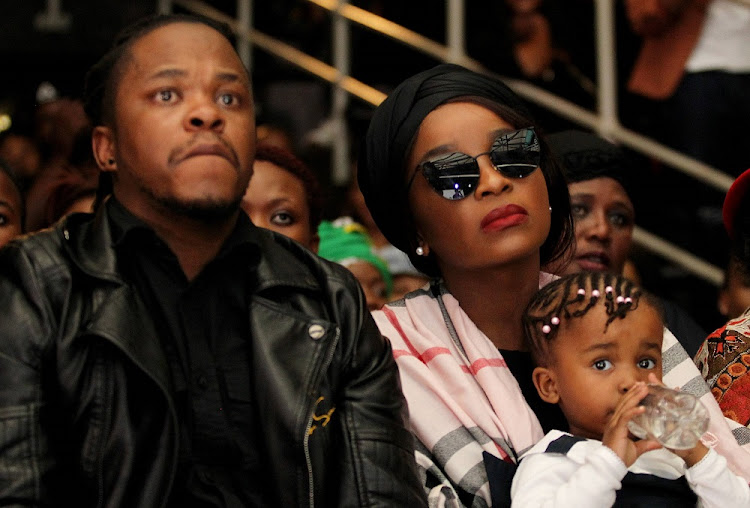ProKid's wife Ayanda holds her daughter Nonkanyezi as she sits next to his brother Sandile Mkhize during his memorial service at Bassline.