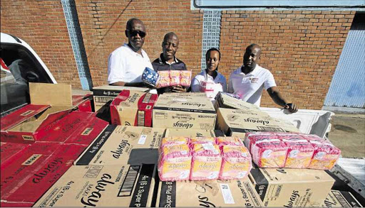 KIND ACT: Lim’uvune Material Supplies Construction Company’s Zondwa Nqokoto, left, Sanele Thomson, third from left, and Xhamla Dyantyi, right,, hand over sanitary pads to Tshepo Machaea as part of the one million pads campaign he and Mzukisi Faleni are coordinating Picture:LULAMILE FENI