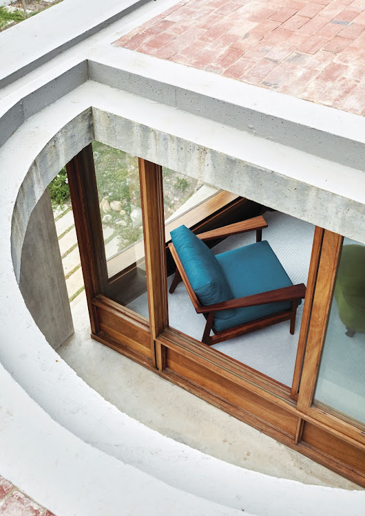 Cut-out, half-circle voids in the top floor allow light and air into the internal courtyard and other outdoor spaces below, while also creating interesting interior perspectives.