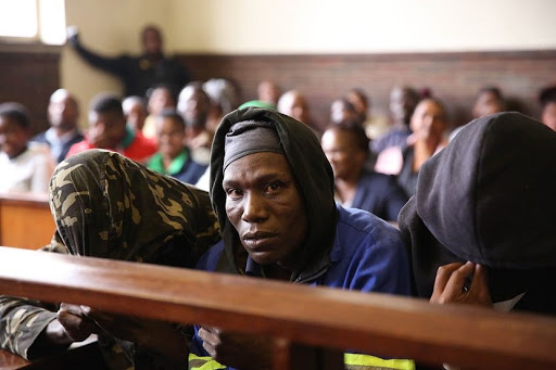 Seven men accused of eating human flash and who are facing charges of murder and attempted murder cower away from cameras while appearing in the Estcourt Magistrate Court on Thursday. Picture: THULI DLAMINI