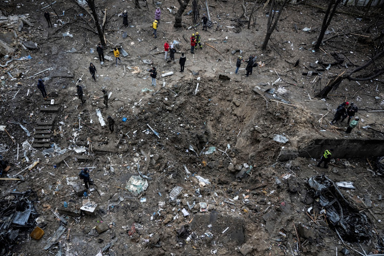 People stand next to a crater at a site of a Russian missile strike, amid Russia's attack on Ukraine, in Kyiv, Ukraine January 2, 2024. Picture: VIACHESLAV RATYNSKYI/REUTERS