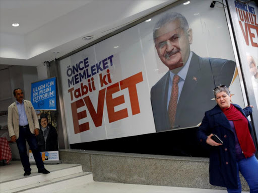 A woman leaves from a campaign office of the ruling AK Party for the upcoming referendum in central Istanbul, Turkey, March 23, 2017. The slogan on the banner with the picture of Turkish Prime Minister Binali Yildirim reads, "Firstly the country. For sure Yes". /REUTERS