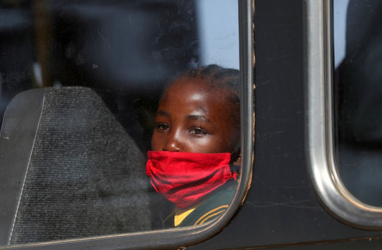 A girl wearing a face mask looks on through a bus window in Eikenhof, south of Johannesburg, as schools reopen during the Covid-19 lockdown in South Africa, on August 24 2020.