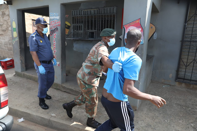 KZN provincial commissioner Lt Gen Khombinkosi Jula looks on as a soldier arrests a man in Inanda, north of Durban, for illegally operating a spaza shop on Monday.